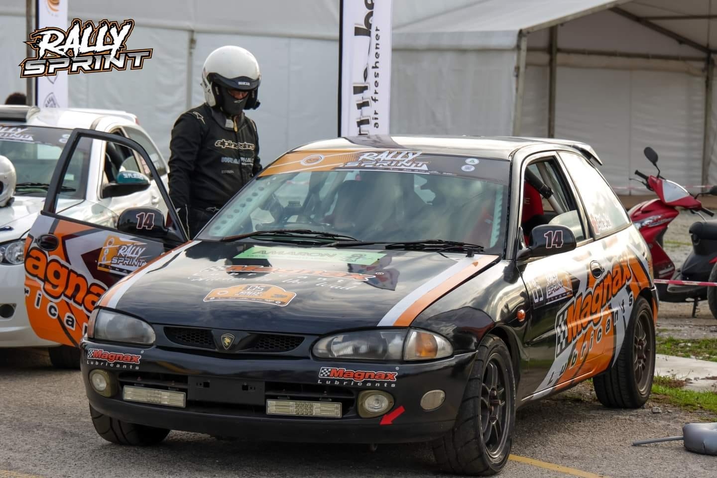 Mitch in race suit with the Magnax Satria rally car at Rally Sprint